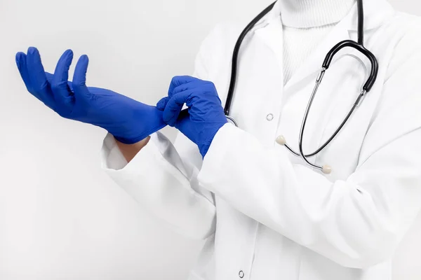 Photo en gros plan d'une femme médecin portant des gants de protection en latex médical sur fond blanc . — Photo