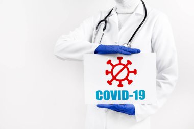 Elinde tabela olan kadın doktor COVID-19 'u beyaz fırının üstünde tutuyor. Coronavirüs salgını ve salgın konsepti.