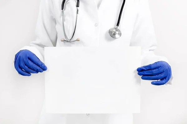 Doctor sosteniendo banner vacío en blanco o póster sobre el suelo de panadería blanco. —  Fotos de Stock