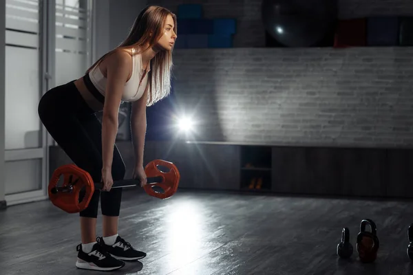 Ajuste mujer rubia joven haciendo ejercicio de barra pesada para la espalda en clase de fitness . — Foto de Stock