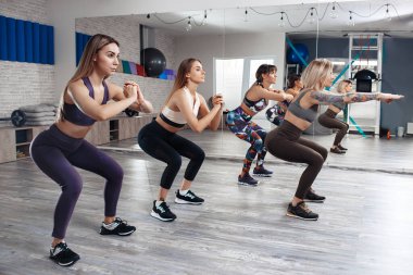 Formda dört genç kız beden eğitimi dersinde kilo verme egzersizi yapıyor. Spor, spor ve yaşam tarzı konsepti.