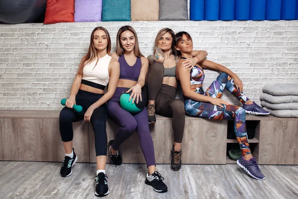 Skupina čtyř mladých fit dívky stojící spolu relaxaci po cvičení ve fitness třídě. — Stock fotografie