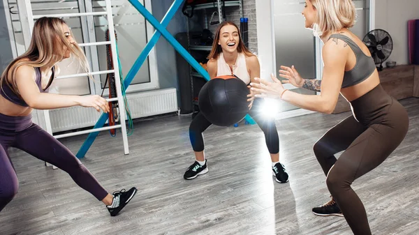 Grupp bestående av tre unga idrottstjejer träning med medicinboll i fitnessklass. — Stockfoto