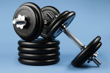 Profesyonel halter ve ağırlık plakaları mavi arka planda. Spor aletleri. Fitness konsepti.