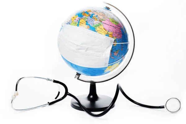 Globe terrestre avec masque chirurgical antiviral et stéthoscope sur fond blanc. Protéger le concept de planète . — Photo
