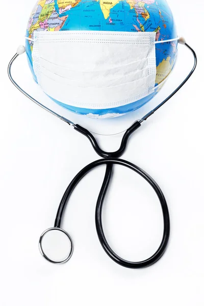 Earth globe with antiviral surgical protective face mask and stethoscope on white background. Protect planet concept. — Stock Photo, Image