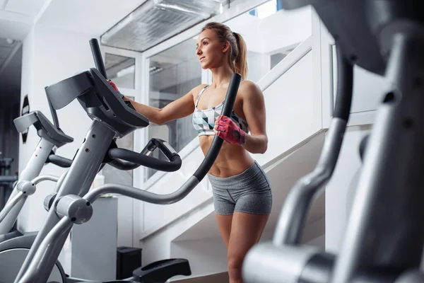 Ajuste mujer joven haciendo cardio en la máquina xtrainer en el gimnasio. Quemadura de grasa. Concepto de salud. pérdida de peso . —  Fotos de Stock