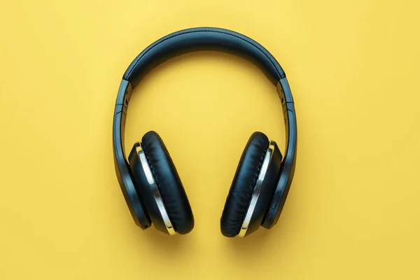 Photo of black stylish modern wireless headphone in neon lights over yellow background. — Stock Photo, Image