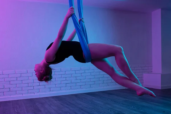 Zarte, fitte junge Frau beim Fly Yoga Stretching mit Hängematte im Yogastudio. — Stockfoto