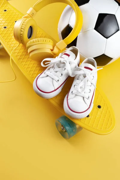 黄色耳机、白色运动鞋和传统风格的足球在黄色背景. — 图库照片