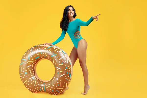 Mayo giymiş seksi bir kadının turuncu arka planda şişirilebilir işaret parmağıyla poz verişi..