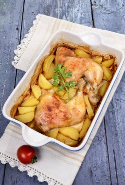 iki kızarmış tavuk budu patates ve bir tepsi ahşap bir masa üzerinde taze yeşil baharat