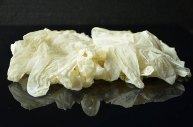 Coronavirus konsepti. Siyah arka planda tek kullanımlık beyaz lateks eldivenler. Koronavirüs salgını sırasında hijyen kuralları. Sağlık ekipmanları konsepti.