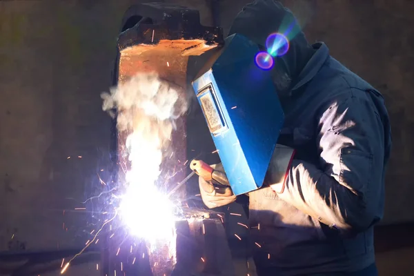 Welding of metal structures ; Welder with protective mask is working on metal welding