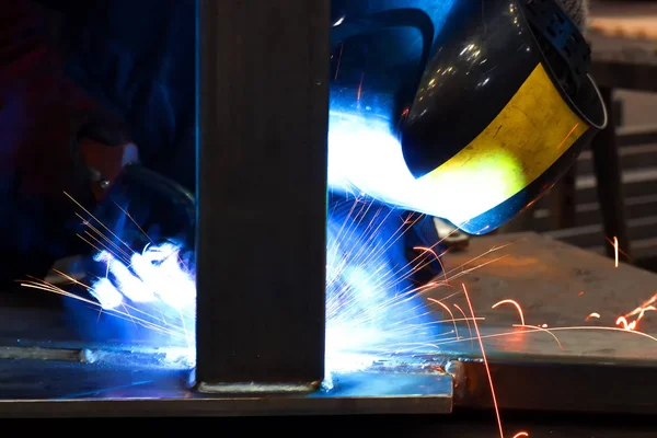 Arc welding of metals ; Welder with protective mask is working on metal welding