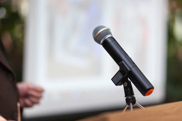 A man stands a with a microphone and holds a conference