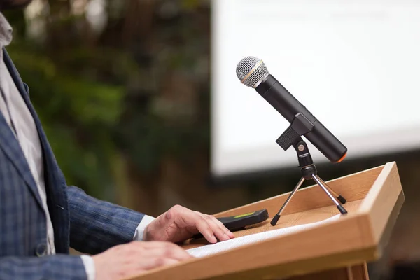 A man stands a with a microphone and holds a conference
