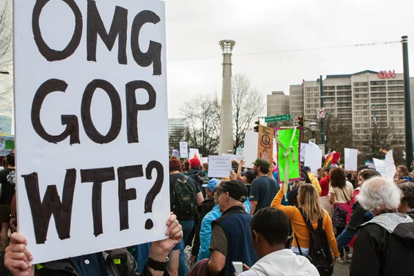 Frau hält Schild in die Höhe, als Demonstranten bei einem Marsch an ihr vorbeigehen — Stockfoto