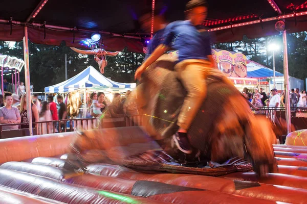 Flou de mouvement de l'homme chevauchant taureau mécanique à la foire du comté — Photo