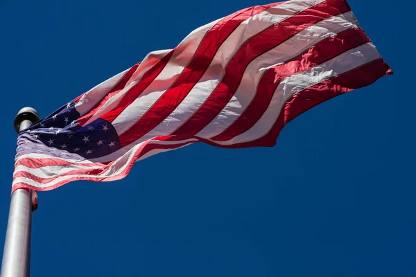 Bandera americana se despliega en interesante patrón en asta de bandera — Foto de Stock
