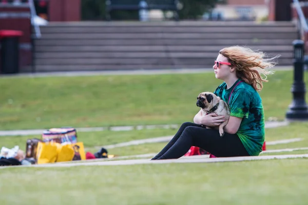 若い女性は、愛情を込めて犬祭りイベントでパグを保持してください。 — ストック写真