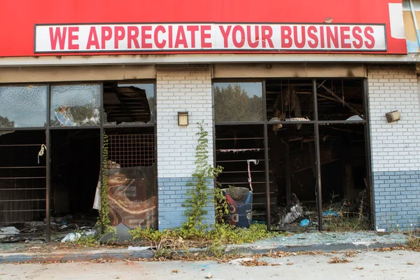 Signe ironique se trouve au-dessus brûlé et vandalisé petite entreprise — Photo