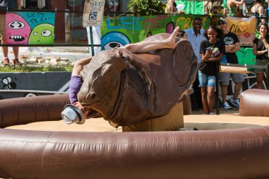 Man Falling Off Mechanical Bull Desperately Holds On clipart