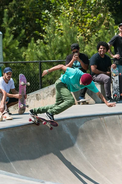 Unga vuxna manliga skateboardåkare sjunker som andra skateboardåkare titta — Stockfoto