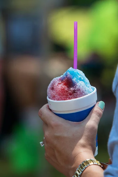 女性の手は、夏祭りでカップの雪コーンを保持しています。 — ストック写真