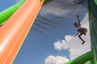 Atlanta, GA, ABD - 10 Ağustos 2019: Kimliği belirlenemeyen bir kız 10 Ağustos 2019 'da Atlanta, GA' da bulunan Piedmont Park 'taki aileler için düzenlenen Fun Day At The Park' ta iki katlı bir şişme kutuda yumuşak bir plastik çukura atlıyor..