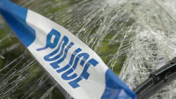 Polis bariyer bandı üzerinde bol dökümlü ile harap bir arabanın ön cam kırık — Stok video