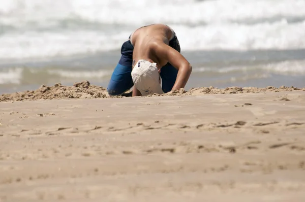 sahilde kum çukuru kazma bir çocuk