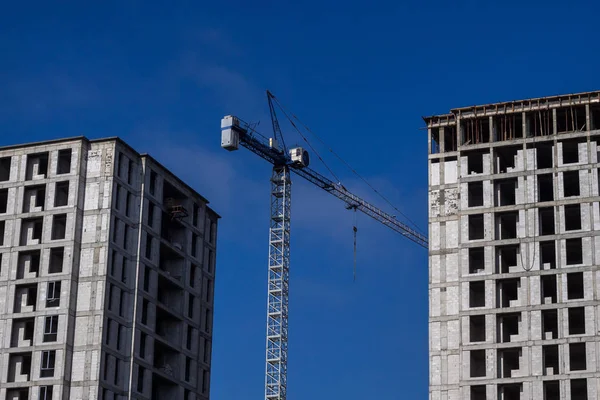 Crane (machine) between two new buildings. Construction of multi-storey houses.