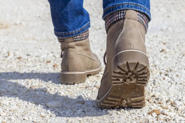 Pu deri botlar, dikiz aynasından. Beyaz kayalık yolda yürüyen botlar.