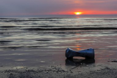 Larnaca, Kıbrıs - Ocak 2020. Güzel gündoğumu sırasında deniz kıyısına bir içki kutusu atıldı..