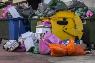 Kaldırımda taşan çöp konteynırları ve çöp torbaları.