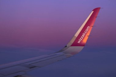 Vilnius, Litvanya - Şubat 2020. Gökyüzünde uçak kanadı. Akşam mor gökyüzünün arka planında Wizz Air logosu.