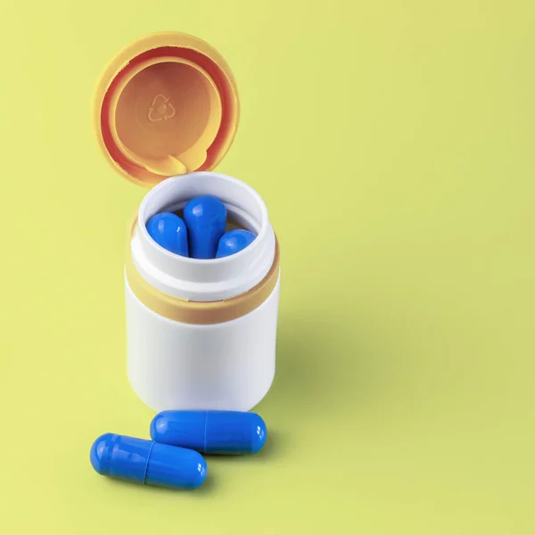 白色塑料瓶 蓝色胶囊 黄色底座 两个胶囊相邻而立 Covid 19概念的假药治疗 — 图库照片