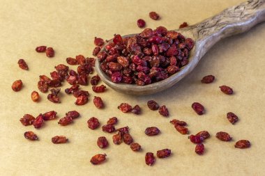 Kahverengi kağıt masa örtüsünün üzerinde seramik kaşıkla kurutulmuş böğürtlen..