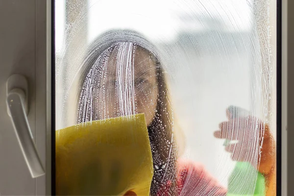 女孩在家里洗窗的轮廓 清理房子的概念 照片通过肮脏的玻璃覆盖洗涤剂 模糊的 — 图库照片