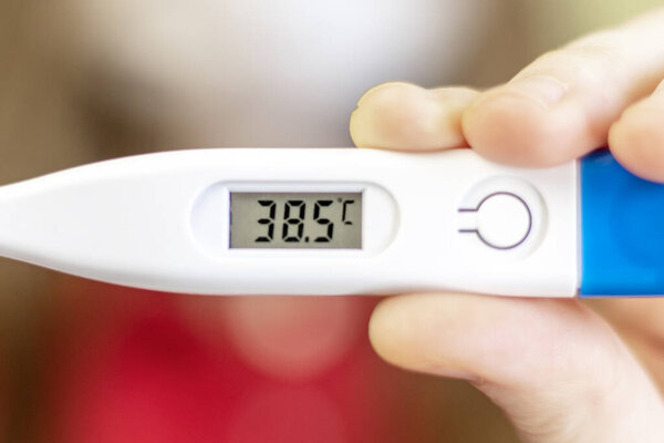 Close up of Digital thermometer in female hand. Concept of illness, fever. Selective focus, blurred background.