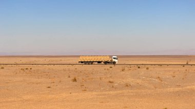 Bir kamyon çölde bir otoyolda gidiyor..