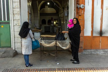 Shiraz, İran - Kasım 2019. Sokak fırınının yanındaki İranlı kadınlar. İnsanlar geleneksel İran pide ekmeği alıyor..