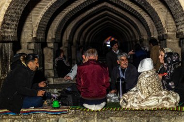 İsfahan, İran - Kasım 2019. Bir grup insan akşamleyin Khaju Köprüsü 'nün altında çay içmek için toplandı..