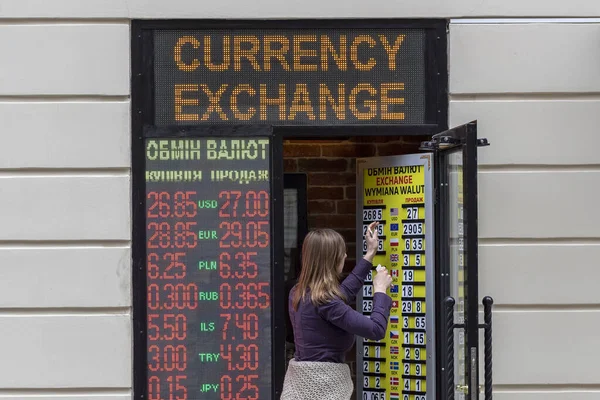 Lviv, Ukrayna - 12 Mayıs 2020. Genç kadın döviz bürosunun borsasında döviz kurlarını değiştiriyor..