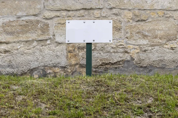 Piastra Bianca Testo Sul Prato Sotto Muro Pietra — Foto Stock