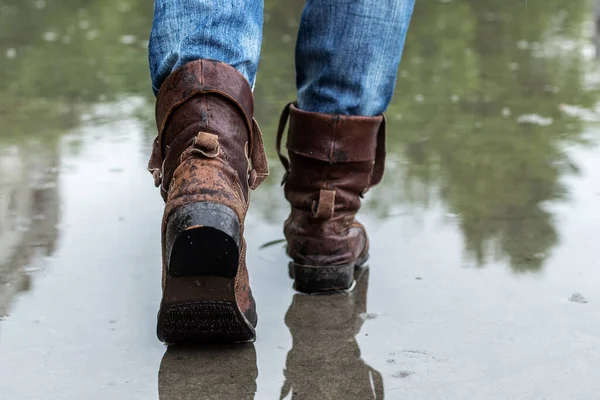 Leather boots on a wet sidewalk in the rain. Close up, rear view.