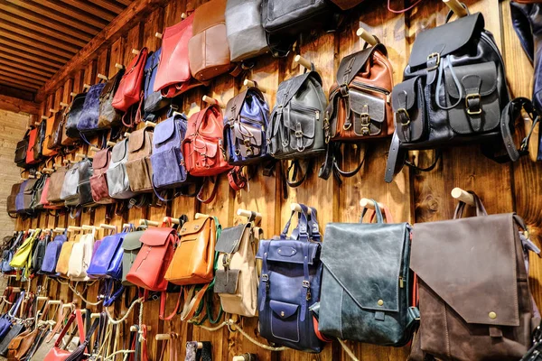 Leather backpacks and briefcases hang on the wall. The concept of stylish  leather products. Bags, purses and belts. Stock Photo by ©Drinkins+  324572168