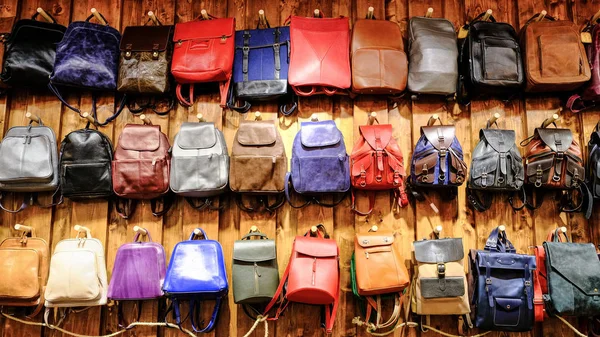 Leather backpacks and briefcases hang on the wall. The concept of stylish leather products. Bags, purses and belts.