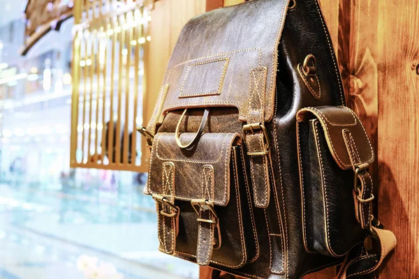 Leather backpacks and briefcases hang on the wall. The concept of stylish leather products. Bags, purses and belts. — Stock Photo, Image